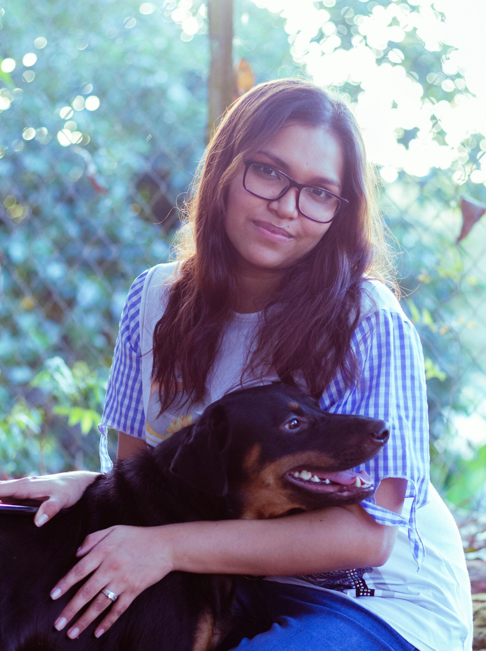 A person hugging a comforting dog on a sofa, both looking at ease.